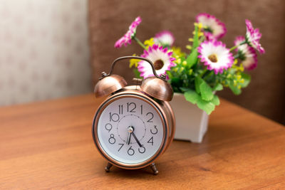 An alarm clock and a small bouquet of flowers in a vase on the bedside table in the bedroom.