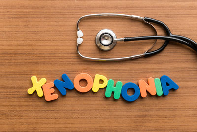 Directly above shot of stethoscope with xenophonia text on wooden table