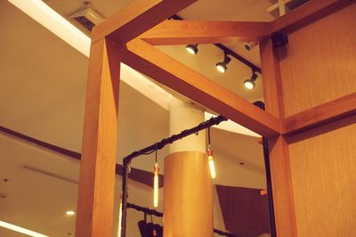 Low angle view of illuminated lights hanging on ceiling of building