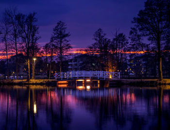 Illuminated bridge over river against sky at night