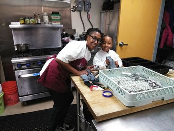 Portrait of female chef with daughter in kitchen