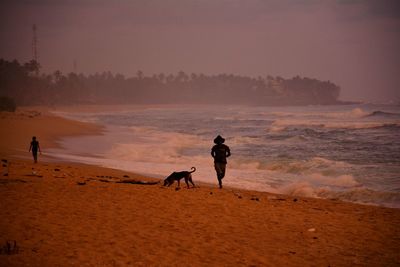 Man running by dog at beach