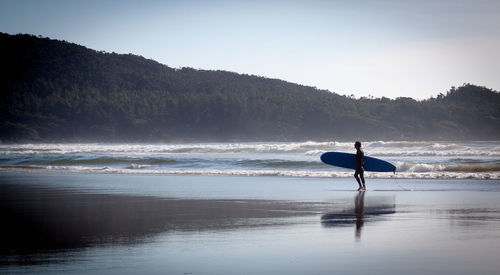 Male surfer walking in calm sea