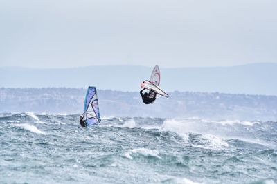 Man surfing in sea against sky