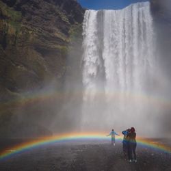 Rear view of man and woman standing on waterfall