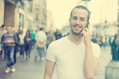 Portrait of young man using smart phone on city street
