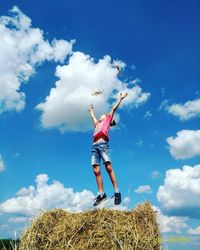 Low angle view of woman with arms raised against sky