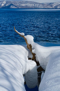 Frozen sea by snowcapped mountain against sky