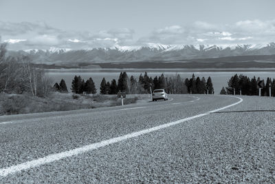 Scenic view of road by field against sky