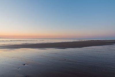 Scenic view of beach against clear sky during sunset