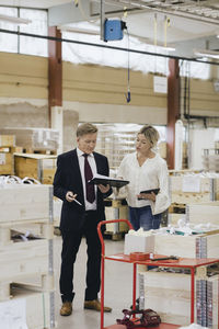 Businessman discussing with female colleague over document in factory warehouse