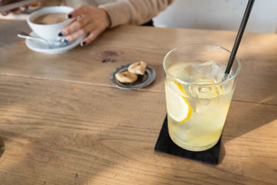 Midsection of woman holding drink on table