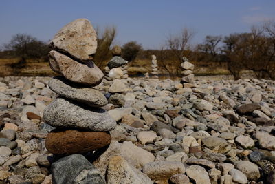 Stack of stones on field against sky