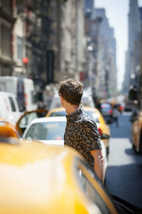 Side view of man standing by cars on road