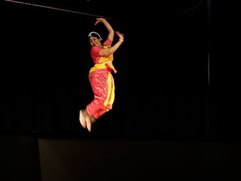 Midsection of woman dancing against black background