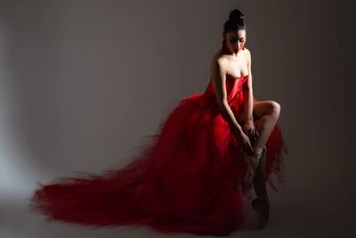 Young woman standing against red background