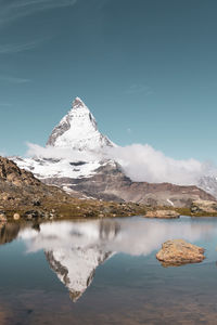 Scenic view of lake by snowcapped mountain against sky