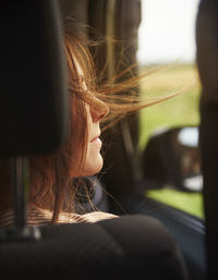 Close-up of woman with tousled hair in car