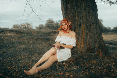 Young woman sitting on tree trunk