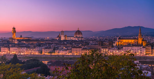 Illuminated cityscape against sky during sunset