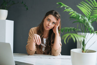 Young smiling woman with dark long hair working at laptop in the bright modern office