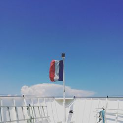Low angle view of flags against clear blue sky