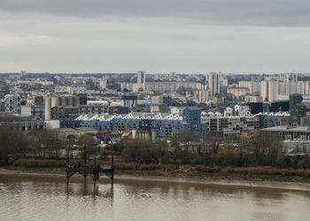 Buildings by river against sky in city