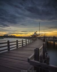 Pier over river against sky during sunset