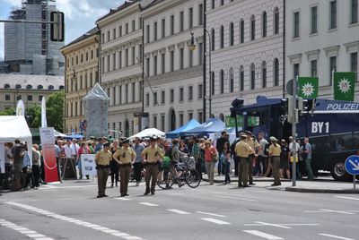 People standing on street by buildings on sunny day in city