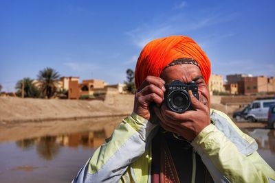 Portrait of man photographing against clear sky