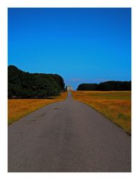 Surface level of empty road against clear blue sky