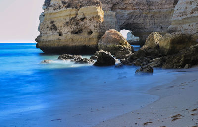 Rock formation on beach against sky