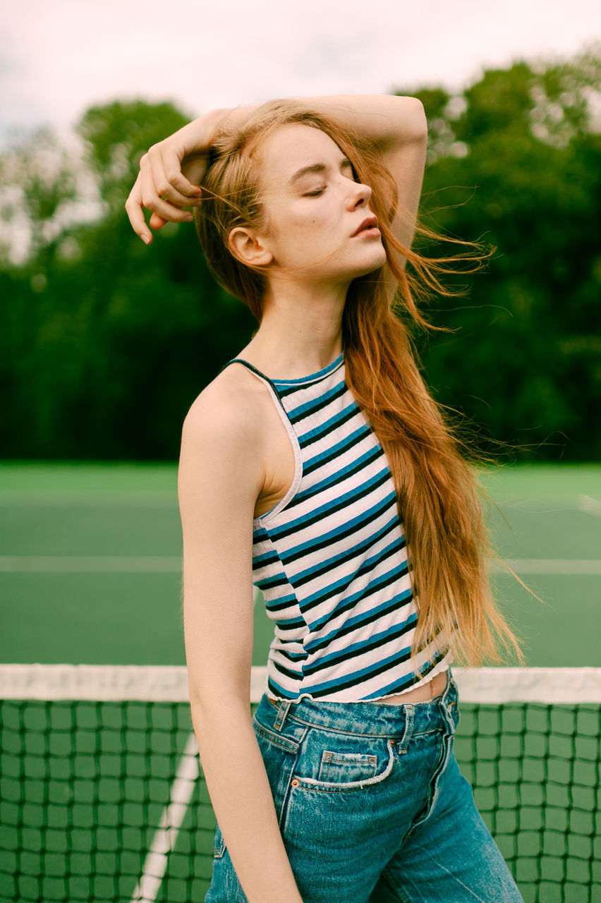 real people, lifestyles, one person, hairstyle, hair, focus on foreground, three quarter length, leisure activity, young women, long hair, young adult, standing, women, day, casual clothing, waist up, tennis, looking, outdoors, beautiful woman, tennis racket