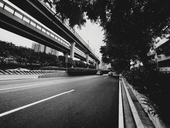 Road by bridge in city against sky