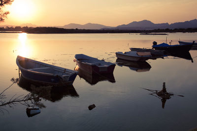 Boats moored on sea against sky during sunset