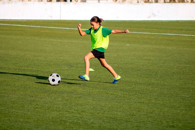 Full length of girl playing soccer on field