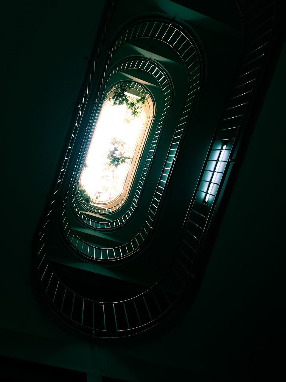 LOW ANGLE VIEW OF ILLUMINATED SPIRAL STAIRCASE IN BUILDING
