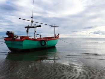 Boats in sea against cloudy sky