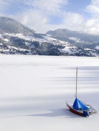 Scenic view of snow covered mountains against cloudy sky