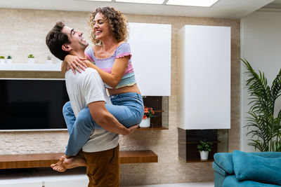 Full length of woman using mobile phone while sitting on sofa at home