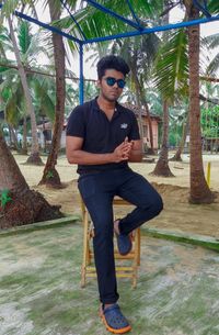 Portrait of young man standing against trees