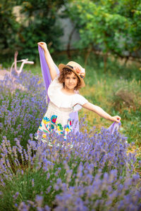 Portrait of young woman standing amidst purple flowers