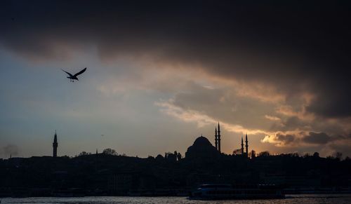 Silhouette airplane flying against sky during sunset