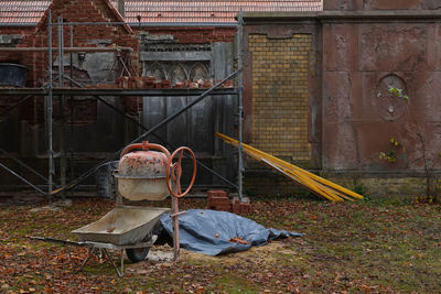 Abandoned wheelbarrow on land against building