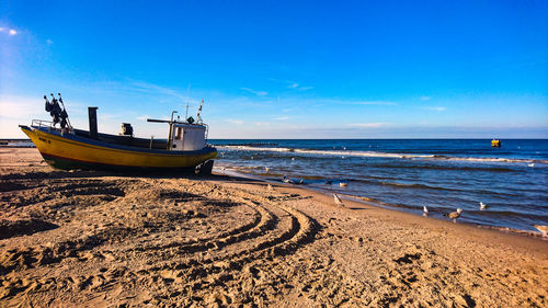 Boat moored on beach against sky