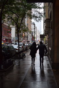 Rear view of people walking on street in city