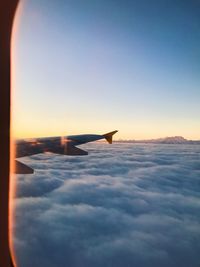 Airplane flying over cloudscape against sky during sunset