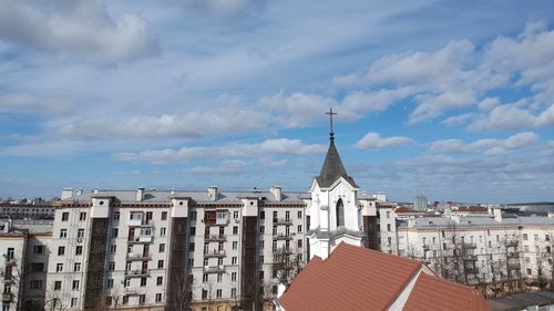 Buildings in city against cloudy sky