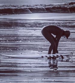 Woman preparing for surfboarding at beach