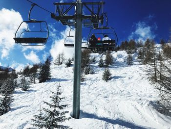 Ski lift over snow covered mountains against sky